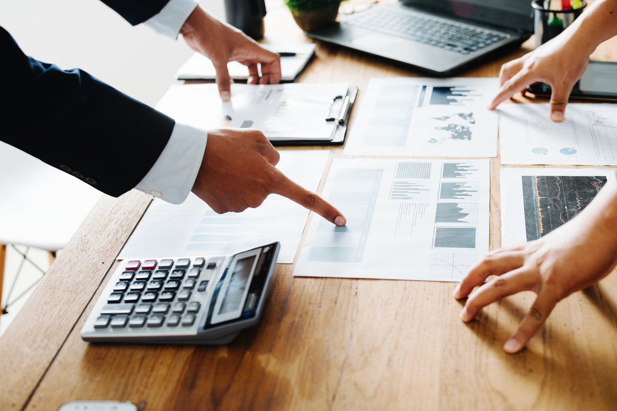 People standing over a conference table pointing to charts