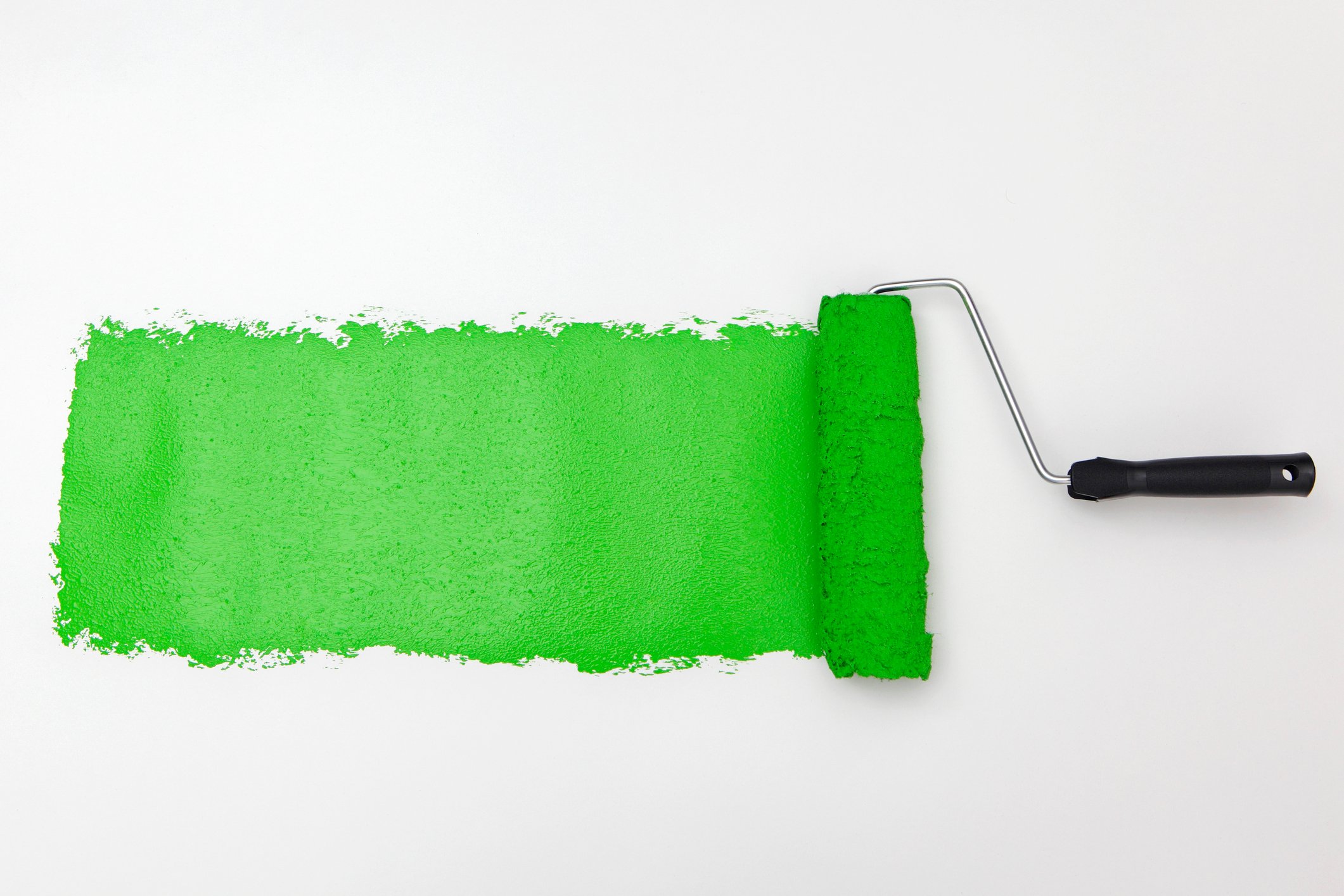 A paint roller adding lime green paint to a white wall