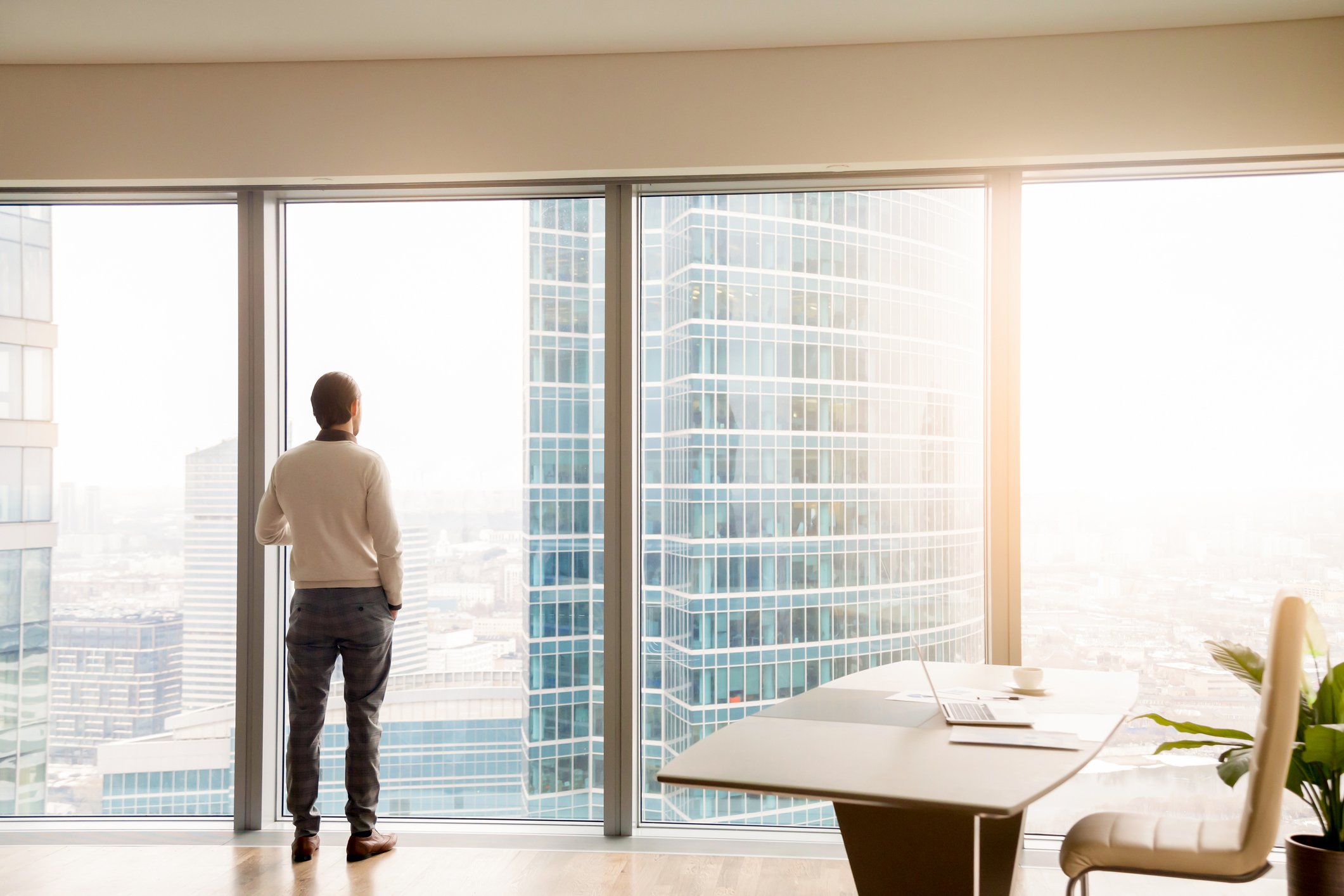 A man looking out of a skyscraper office window.