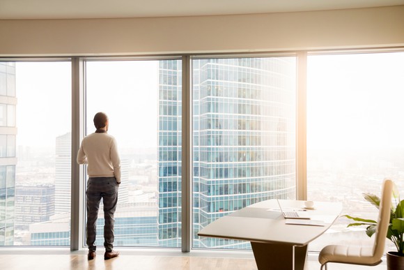 A man looking out of a skyscraper office window.