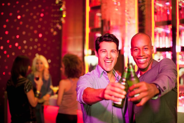 Two men holding bottled beers.