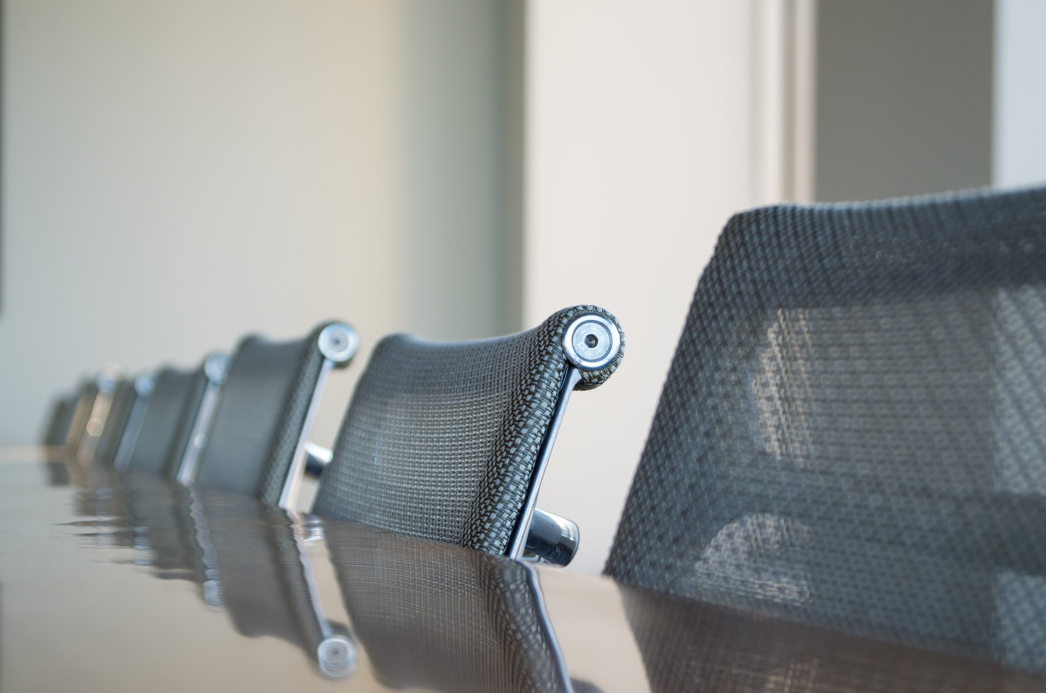 Office chairs pulled up in a row at a table.