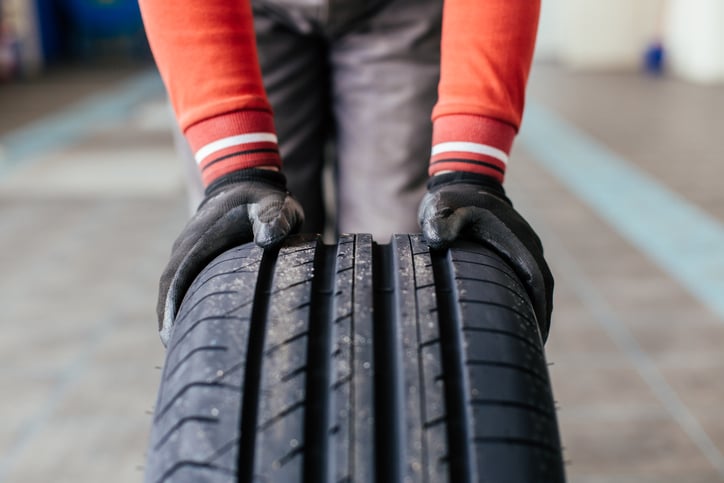 Gloved hands rolling a car tire.