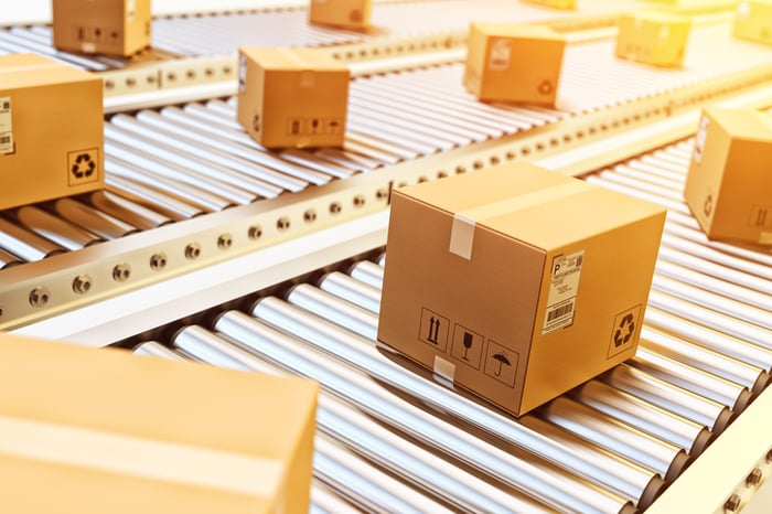 Cardboard boxes taped shut and moving down a conveyor.