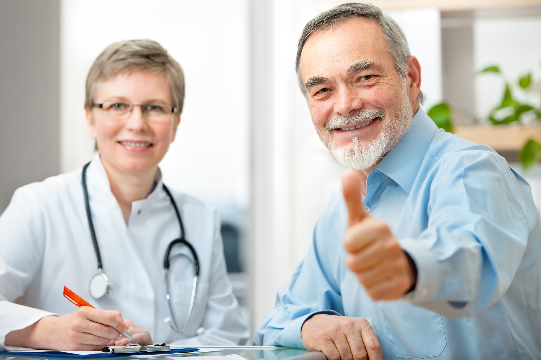 A patient gives a thumbs up as he and his doctor smile.