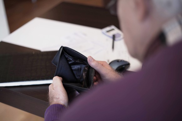 Senior man looking into empty wallet.