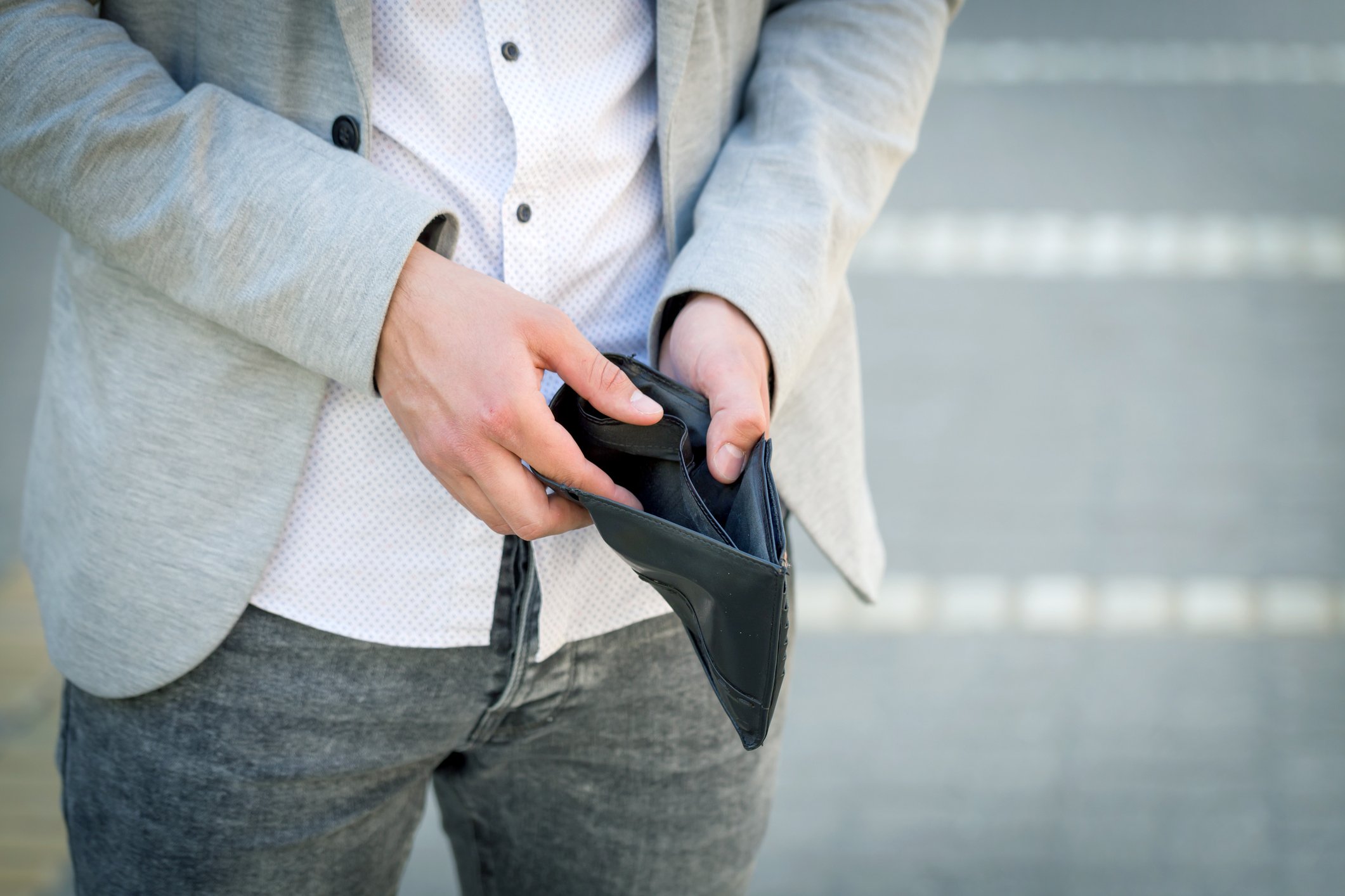 Man holding open a wallet to reveal that it's empty