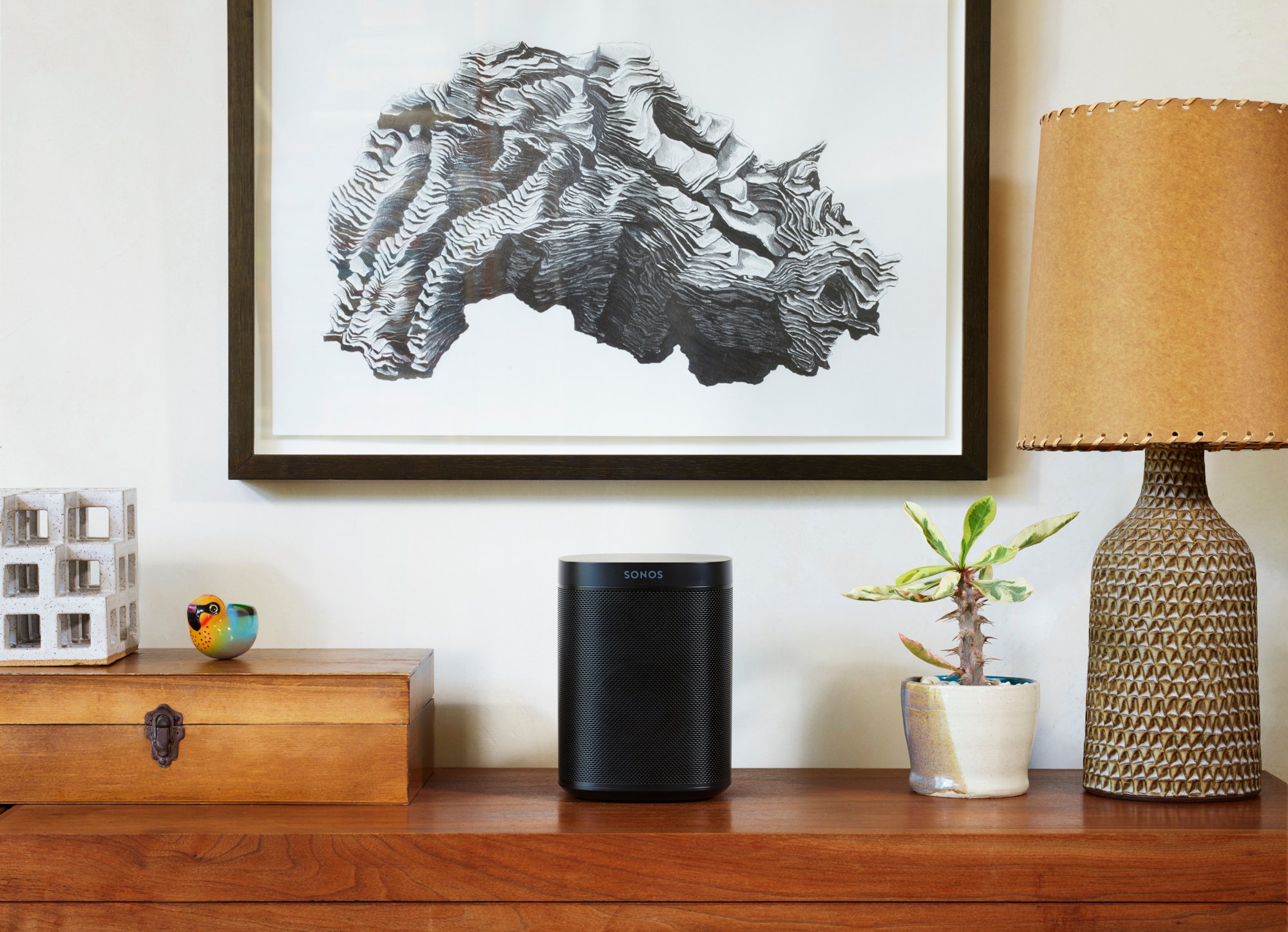 Sonos One sitting on a shelf beneath a painting