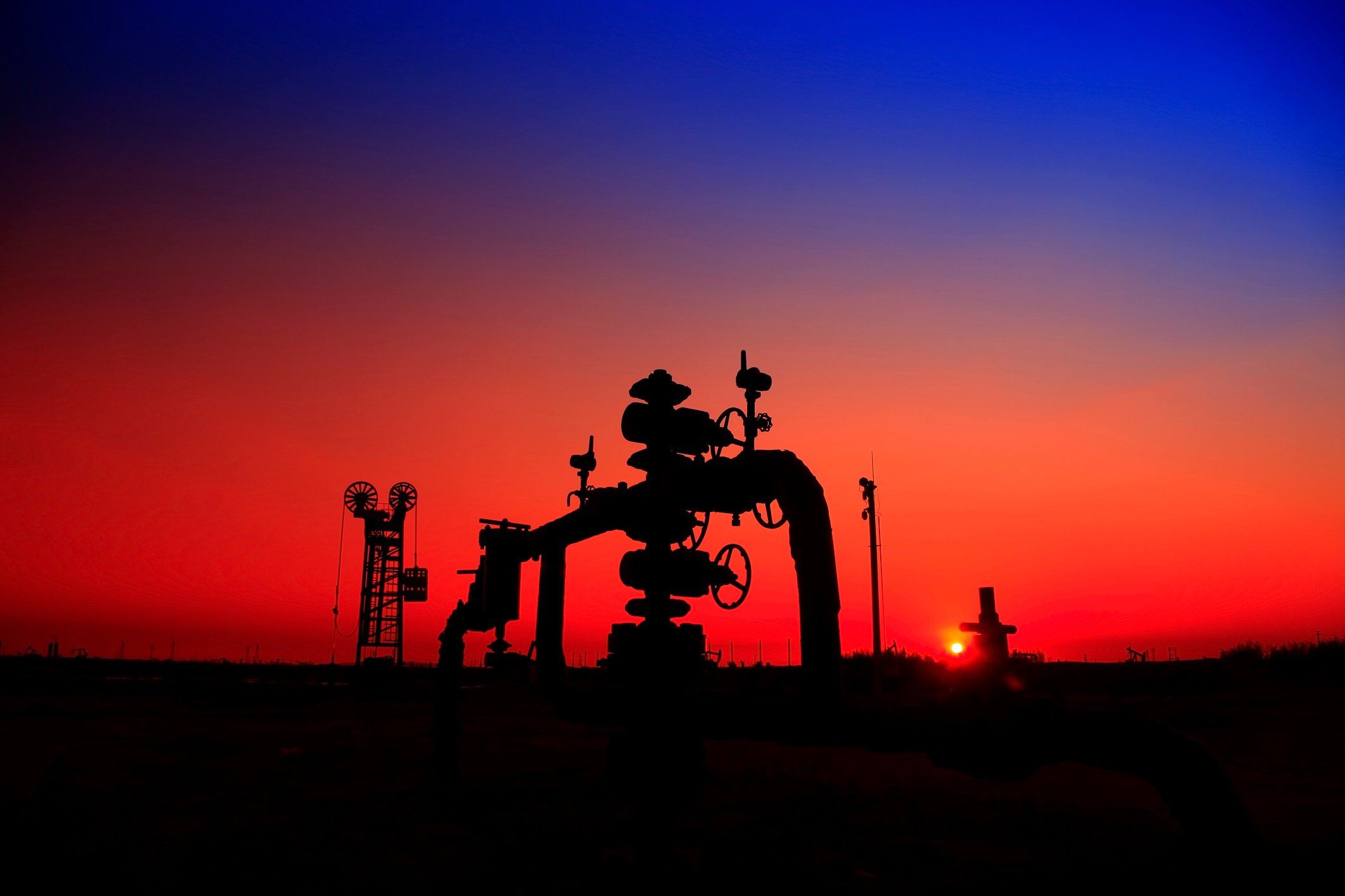 The silhouette of a natural gas well at sunset.
