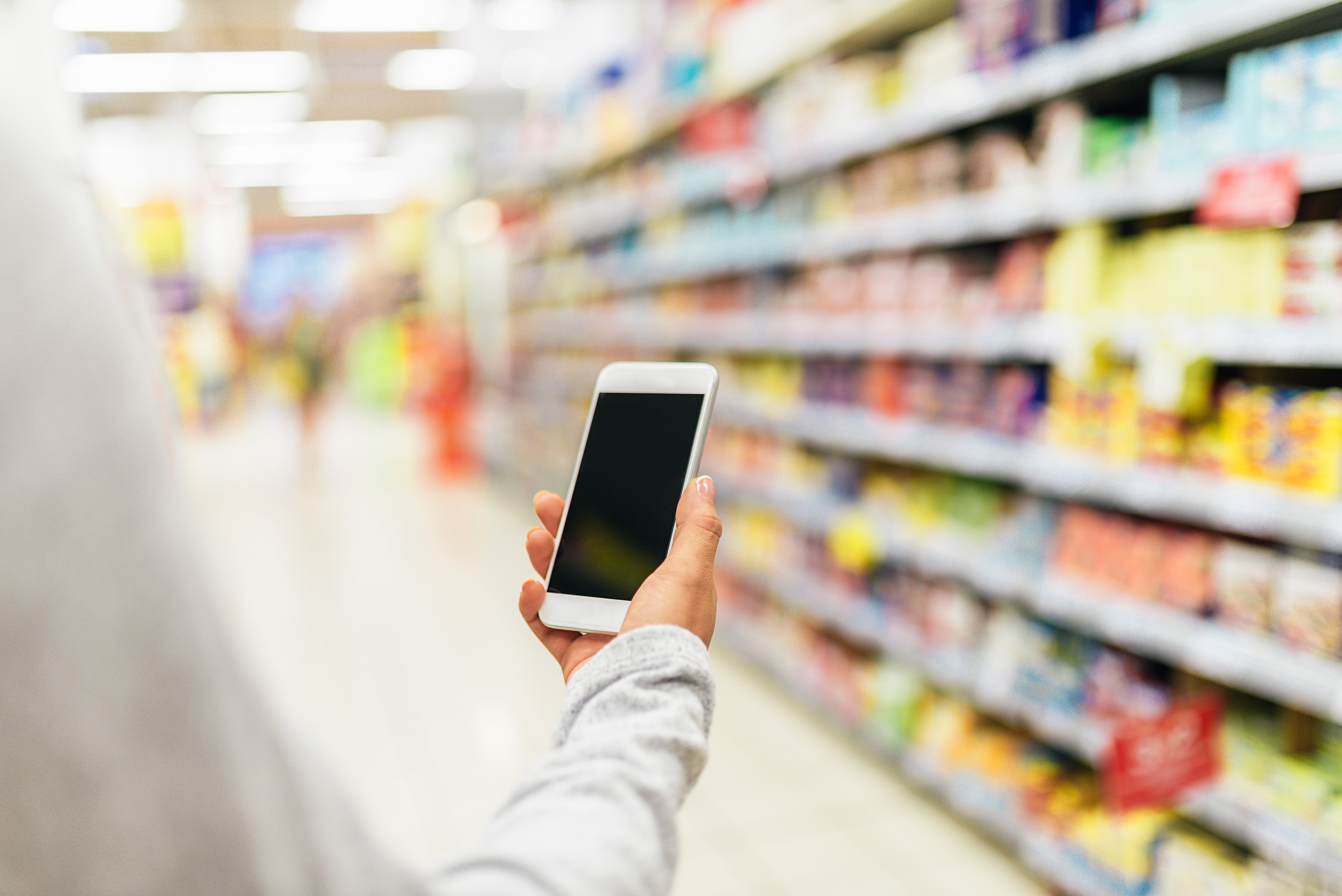 A man checks his smartphone while shopping.