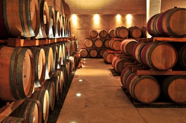 Rows of Wooden Wine Barrels in Well-Lit Cellar