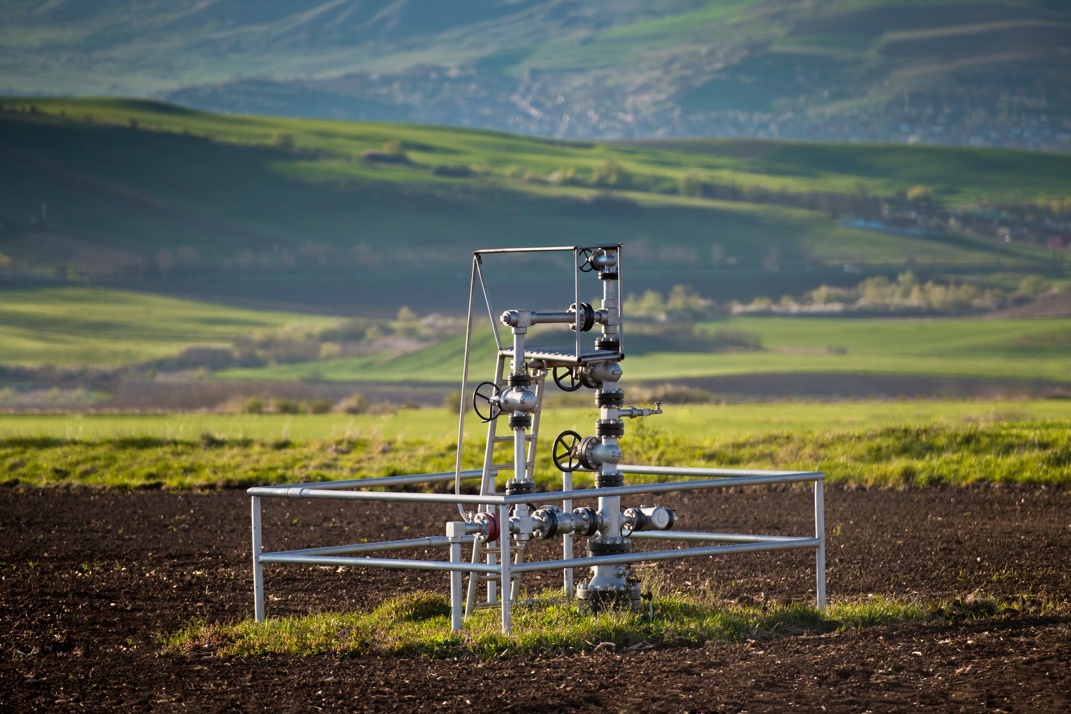 A natural gas wellhead in the middle of a field.