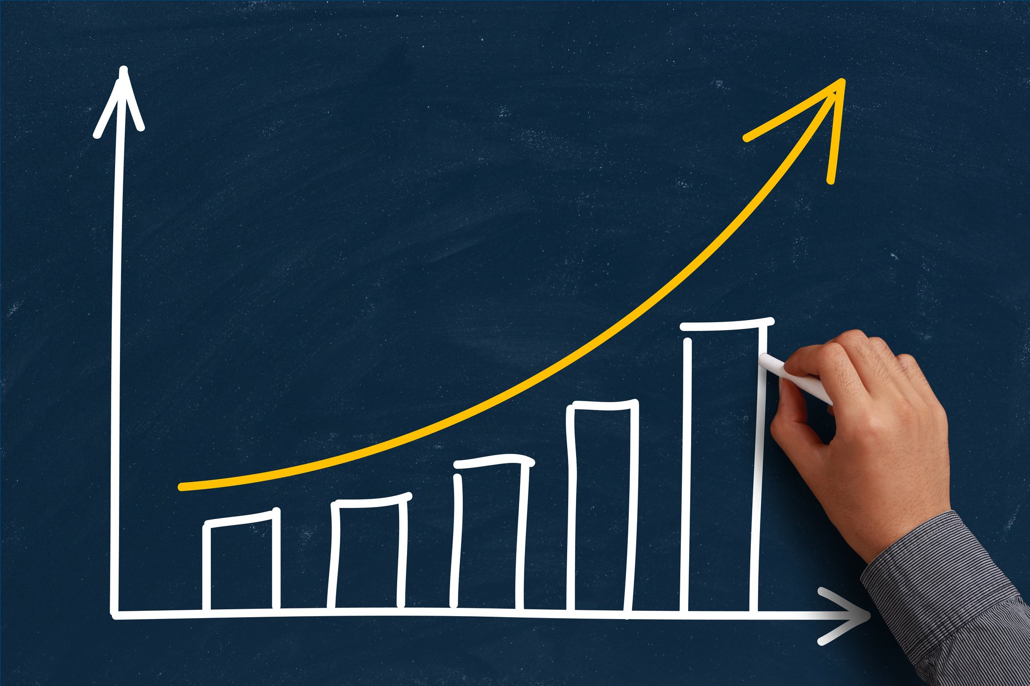 A hand drawing a rising bar chart on a blackboard.
