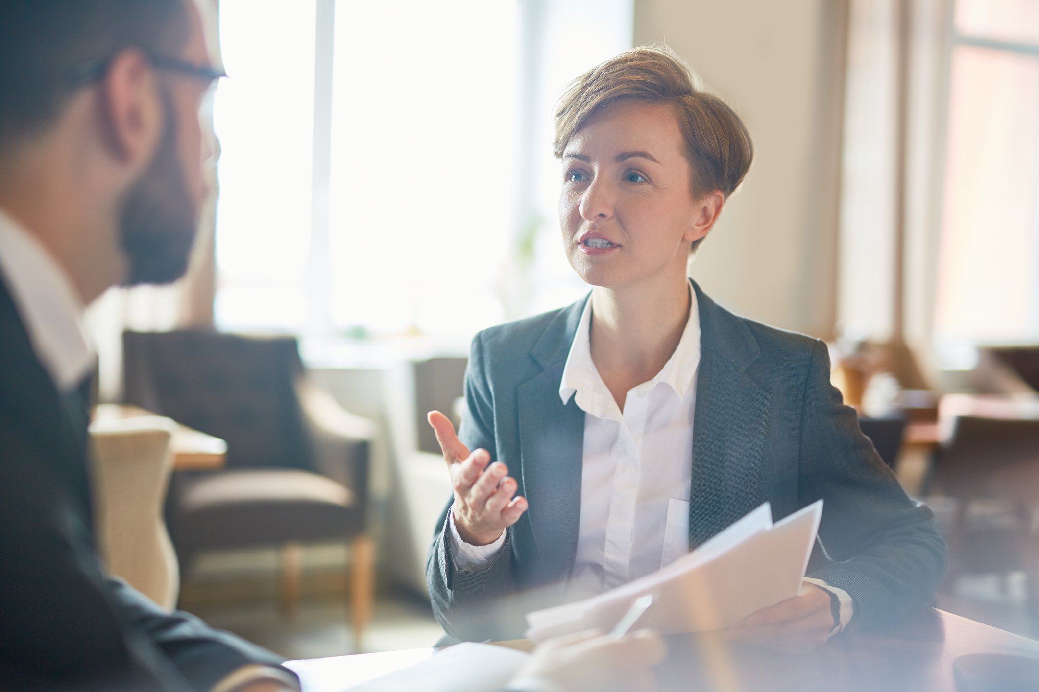 Professional woman holding papers while talking to a professional man