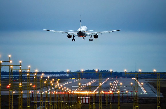 An airplane prepares to land on a runway at twilight.