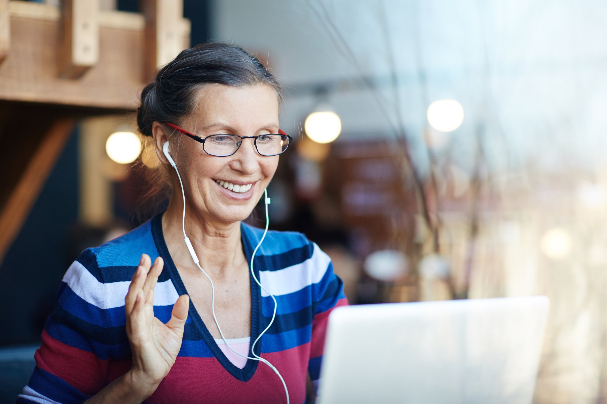 An older woman waving at a laptop screen