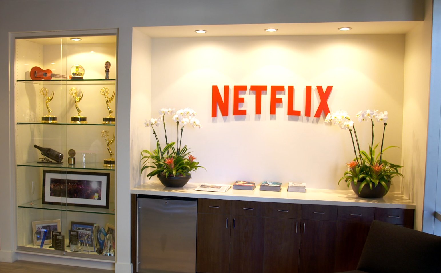 A few shelves displaying a handful of Emmy statuettes and other awards next to a large red Netflix logo.