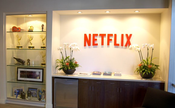 A few shelves displaying a handful of Emmy statuettes and other awards next to a large red Netflix logo.