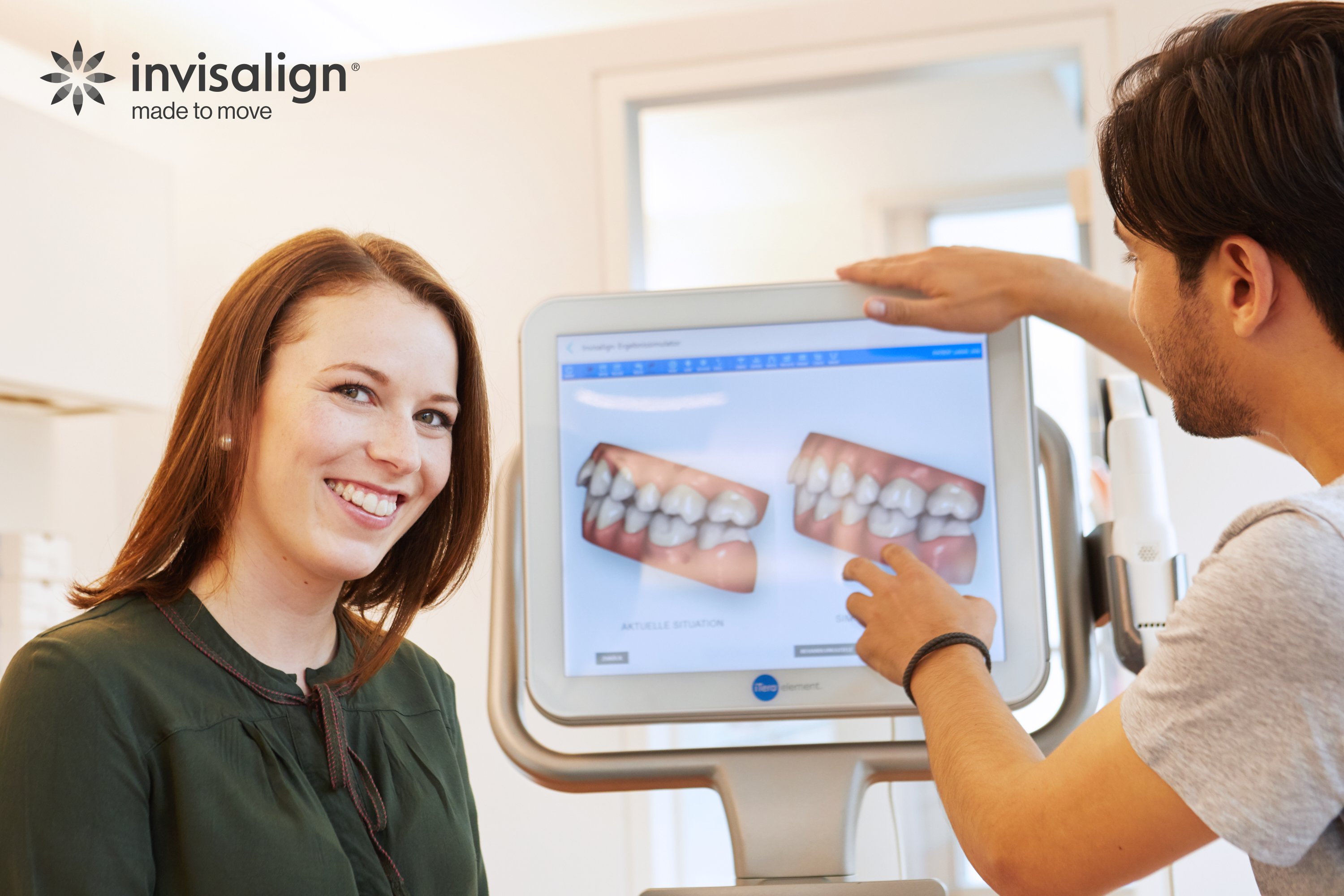 A woman smiling as an orthodontist shows images on a computer screen of before and after images of straightened teeth.
