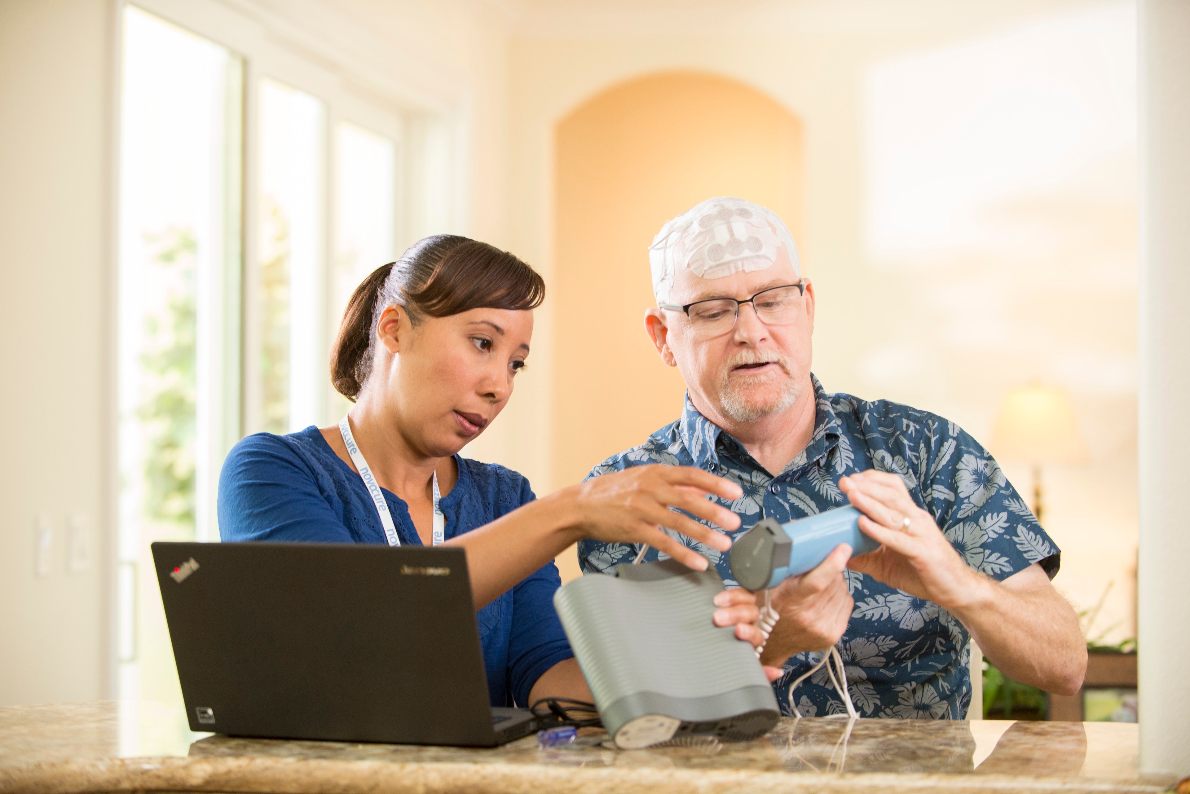 Healthcare provider and patient using Novocure's Optune device.