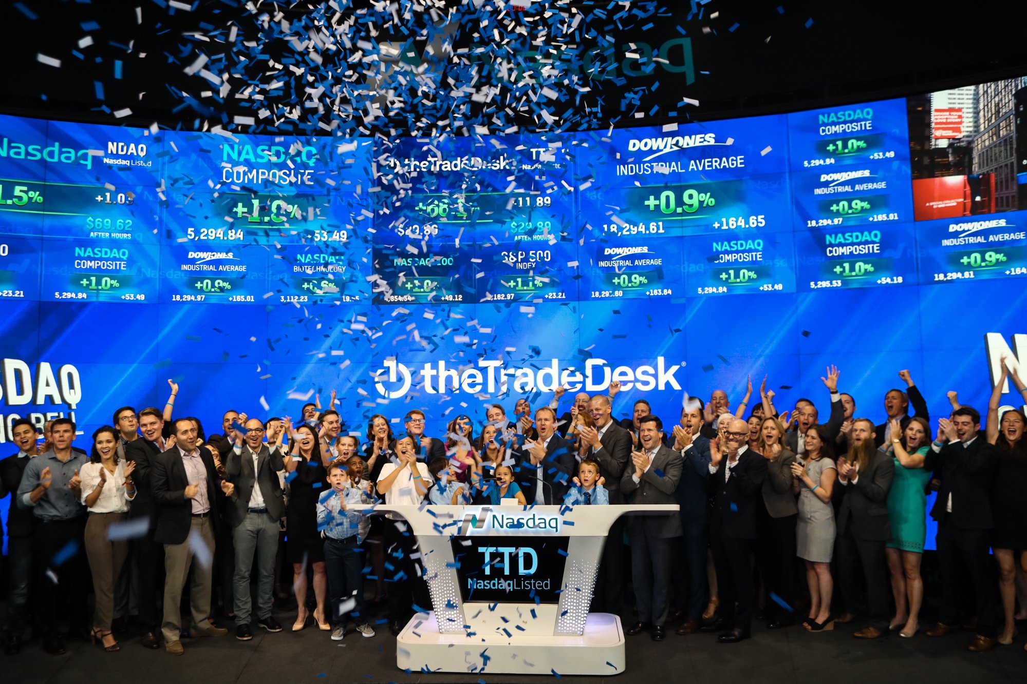 People cheering and waving as confetti rains down, as The Trade Desk Executives ring the NASDAQ opening bell for its IPO.