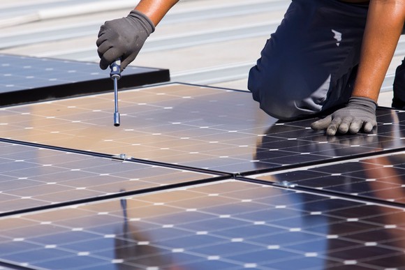 A worker installing solar panels on a roof.