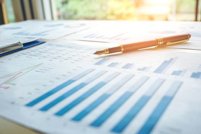 A pen sitting on top of papers displaying graphs and data.