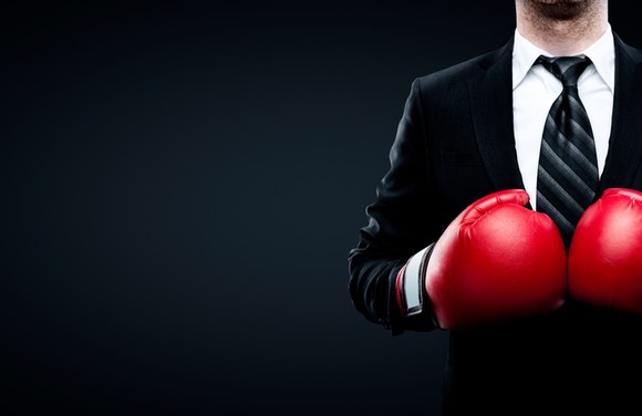 A businessman wearing red boxing gloves.