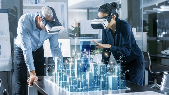A man and a woman view AR models of buildings with headsets.
