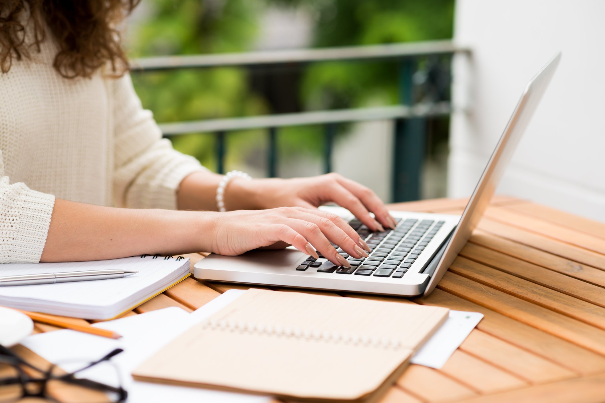Woman typing on a laptop outside