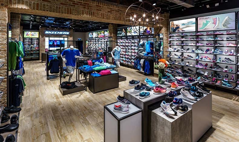 The interior of a new Skechers store. Shoes are on display on tables and on wall shelves.