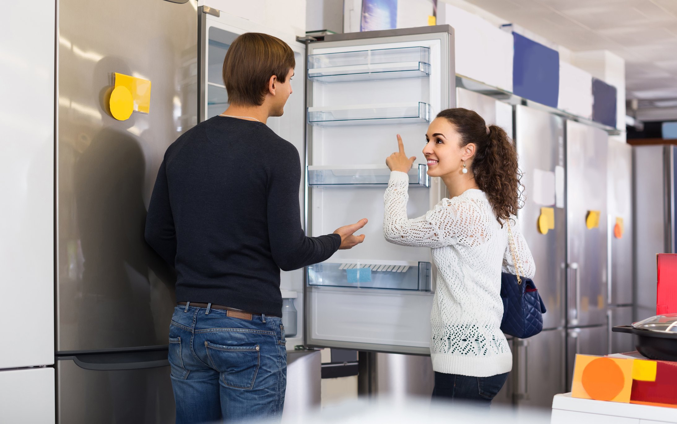 Man and woman looking at refrigerators in a store.