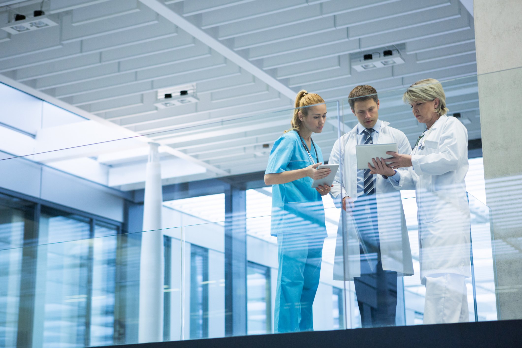 Medical professionals looking at tablet in a building corridor.