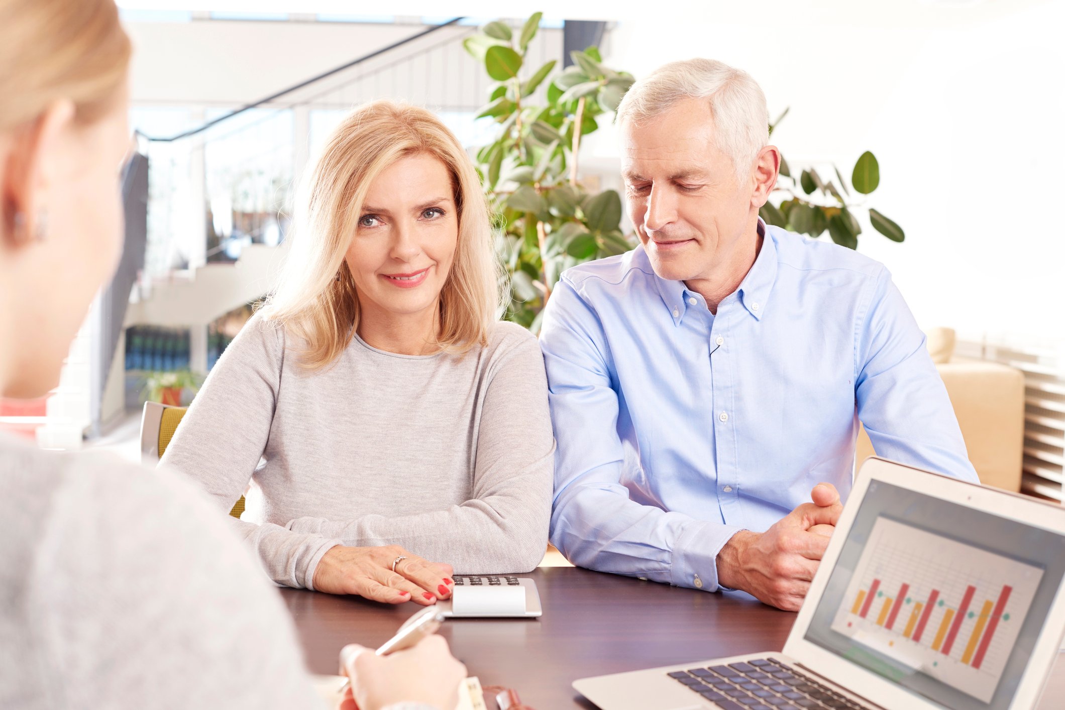 Older couple sitting across from woman with a laptop showing bar graphs