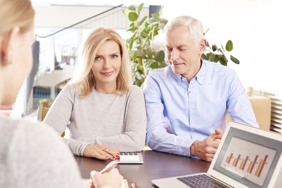 Older couple sitting across from woman with a laptop showing bar graphs