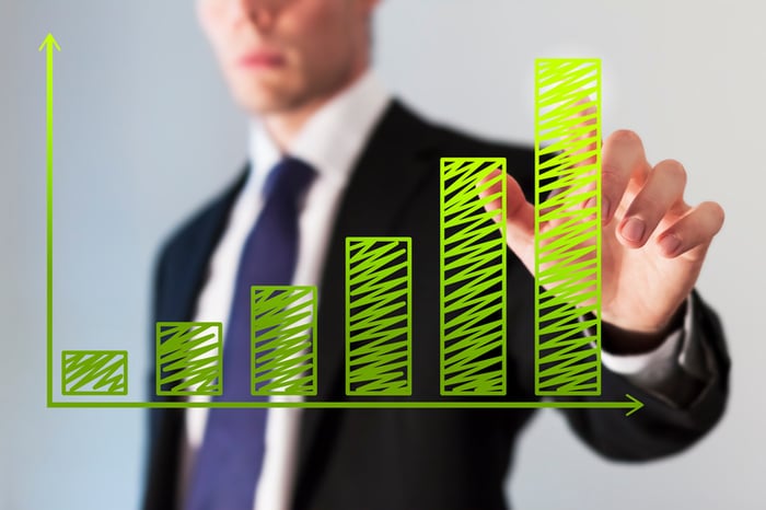 A person in a suit viewing a column chart on a transparent board.