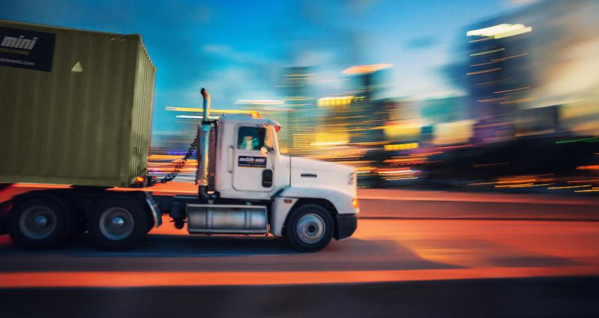 A Mobile Mini truck moving against a blurred background.