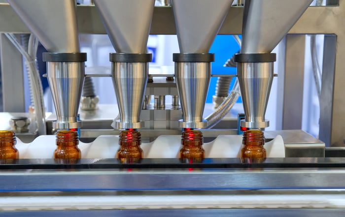 Pills are dispensed into bottles on a conveyor belt