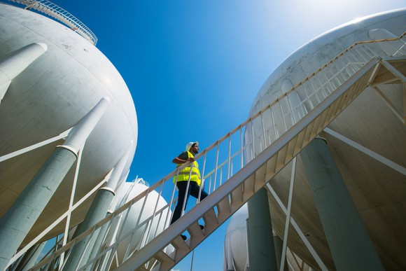 A worker climbing stairs to inspect LPG tanks.