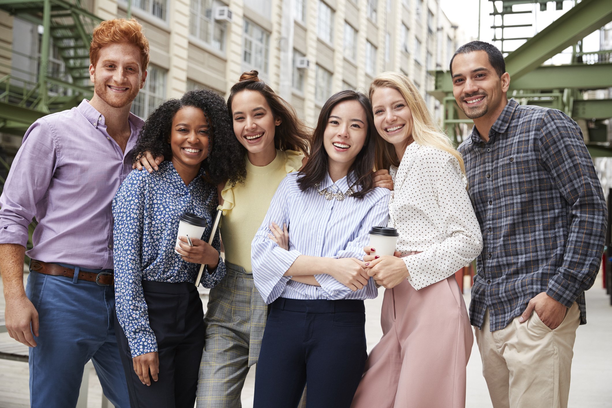 A group of young people smiling as they stand together outdoors.
