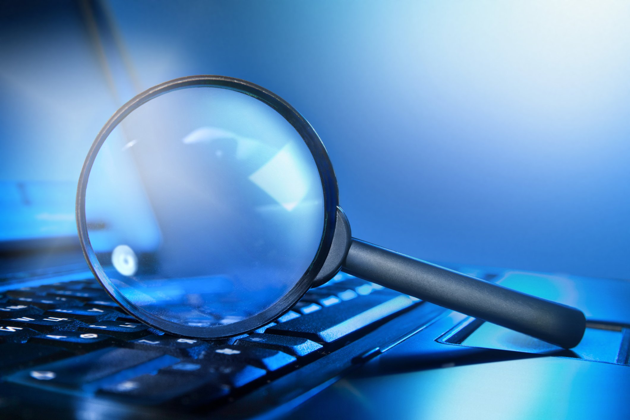 Magnifying glass resting on a laptop PC.