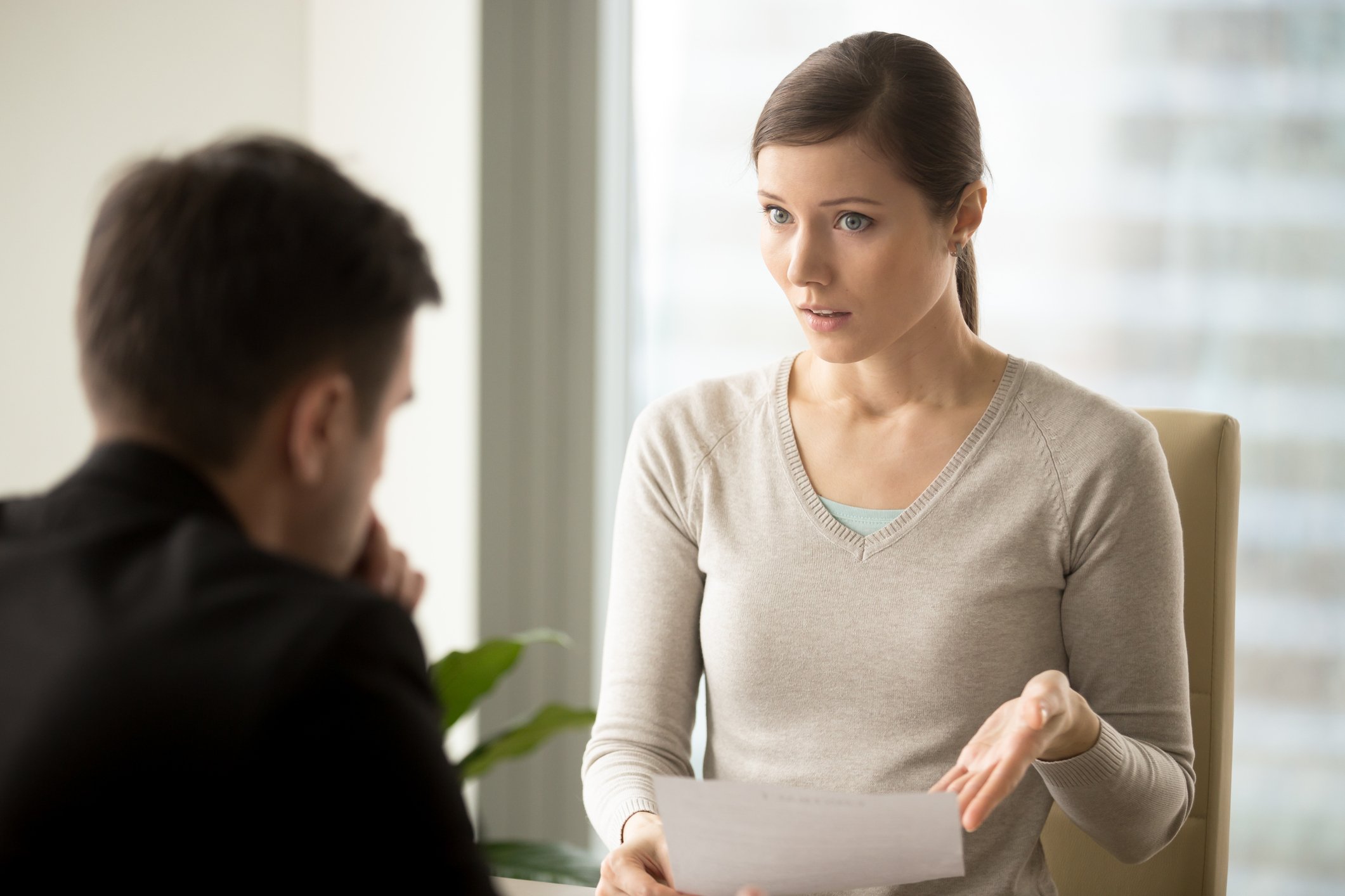 Professional woman showing professional man a document with disapproving expression.