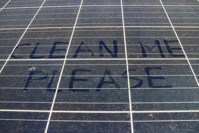 Dusty solar panel with clean me please written in the dirt.
