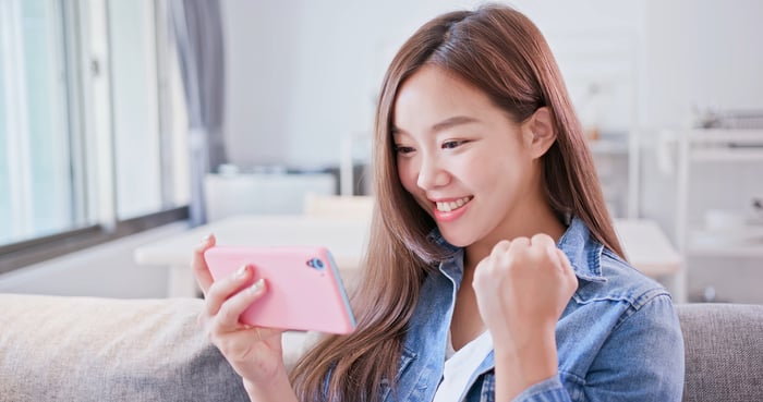 A young woman plays a mobile game.