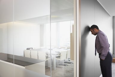MAn with head against wall in conference room