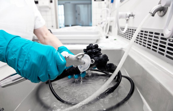 A person with rubber gloves working at an industrial sink.