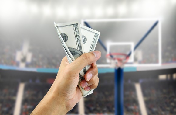 Person holding money up on basketball court. 