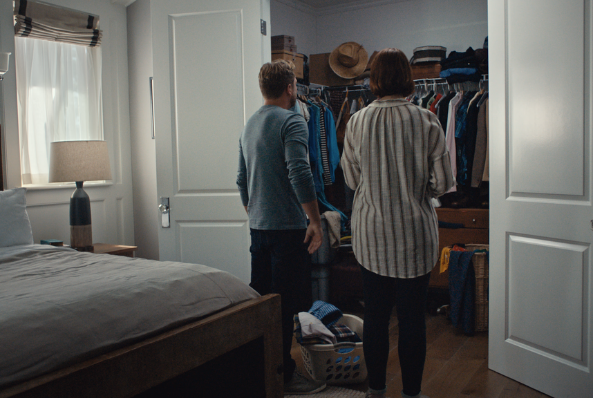 A couple looks into a messy closet. 