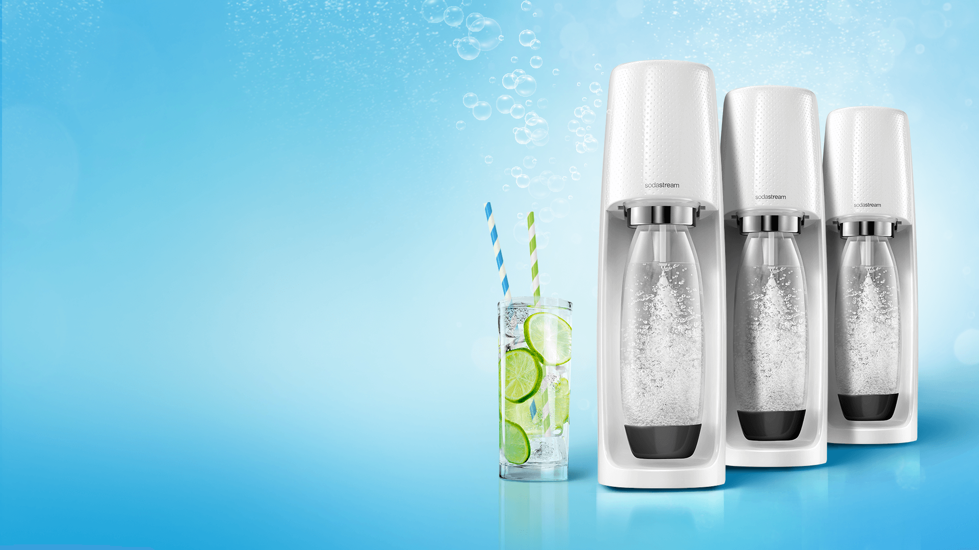 Three SodaStream water makers next to a glass of water with lime and two straws.