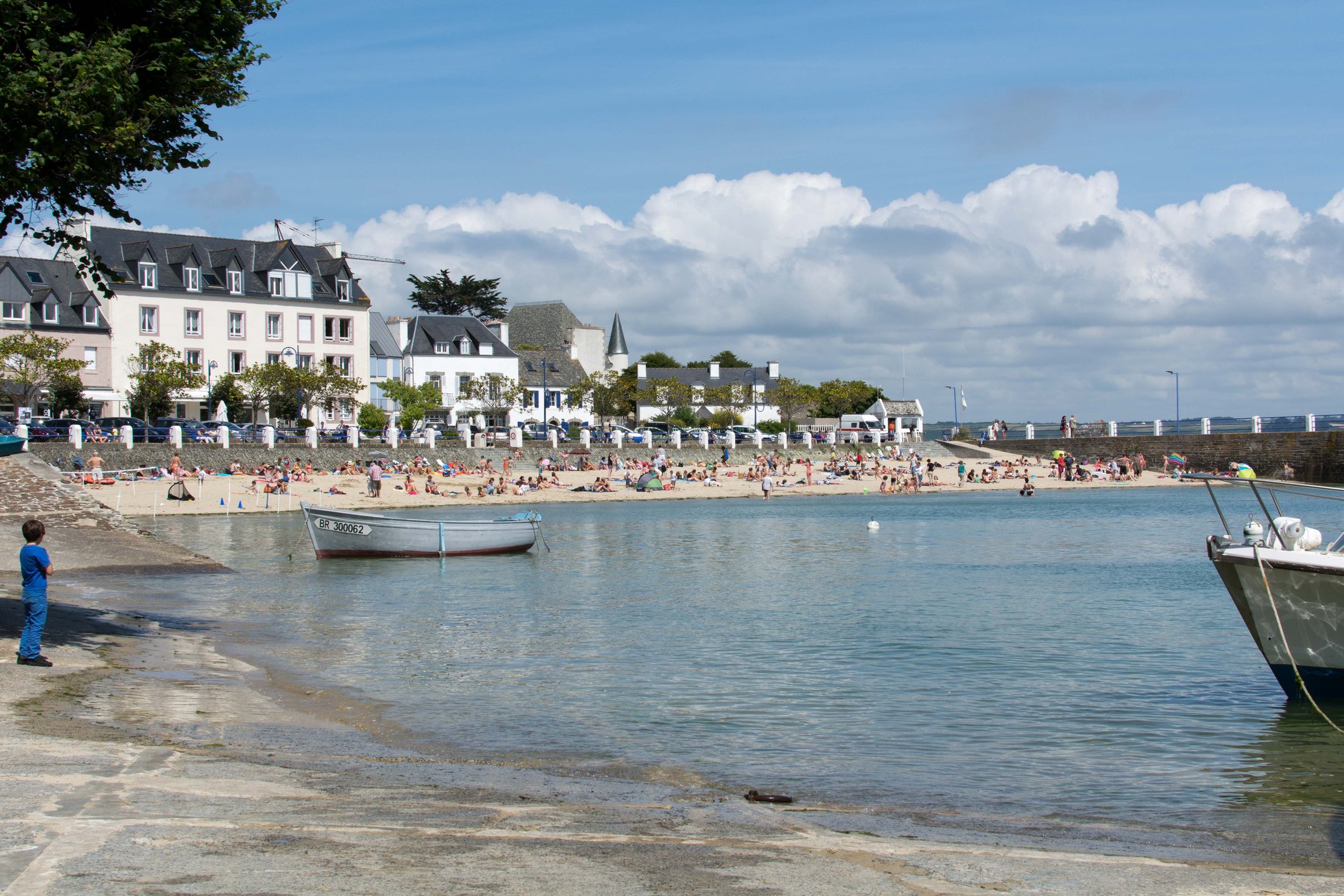 Beachside resort with manor house and boats in shallow bay.
